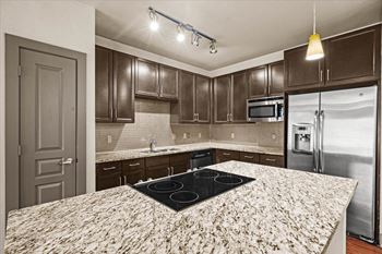 A kitchen with granite countertops and dark wood cabinets
